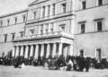 Πρόσφυγες έξω από τα παλιά ανάκτορα της Αθήνας, το 1922. Στο κτήριο λειτουργούσαν υπηρεσίες αρωγής και αναζήτησης αγνοουμένων συγγενών (φωτ.: Library of Congress / American National Red Cross)